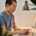 A Man in Blue Shirt Using a Laptop