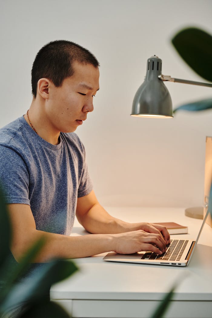 A Man in Blue Shirt Using a Laptop